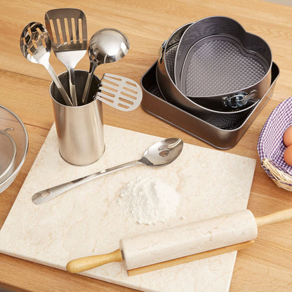 Kitchen utensils and tools on a wooden table including a rolling pin, measuring cups, and a basket of eggs.