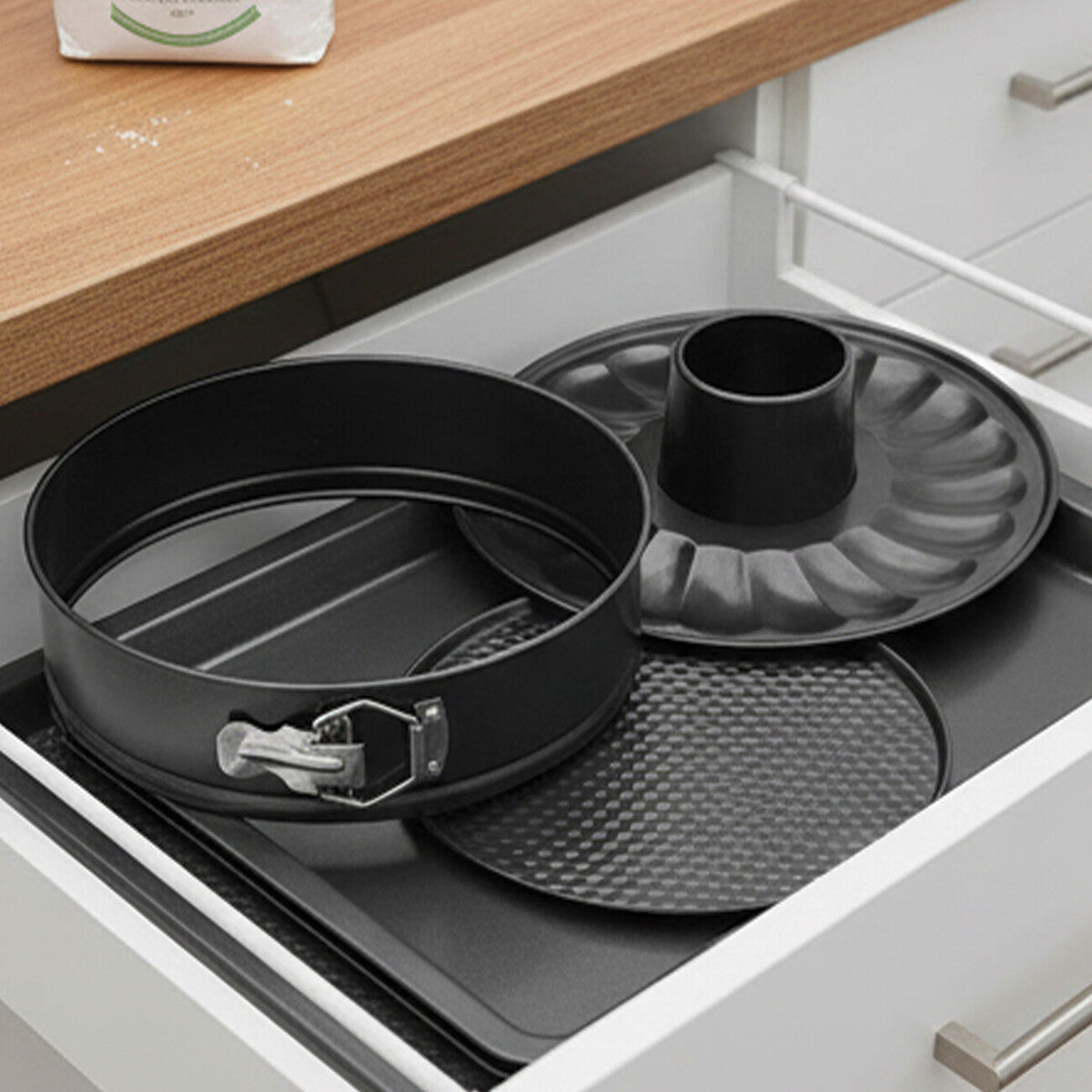 Set of baking pans including a round cake pan and a bundt pan in an open kitchen drawer.