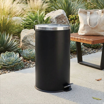 Black outdoor trash can with a wooden bench and plants in the background