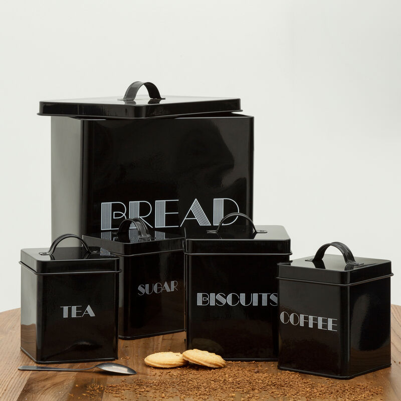 Set of black kitchen canisters with labels on a wooden surface