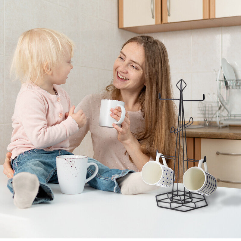 Woman and child in a kitchen with mugs and a mug rack.