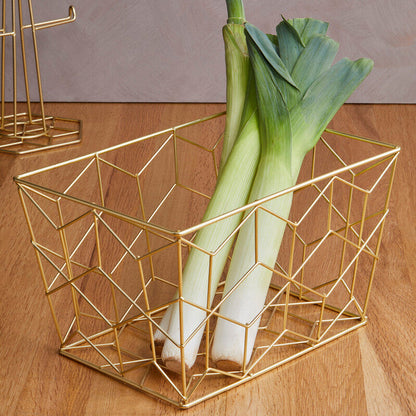 Gold geometric wire basket with leeks on a wooden surface