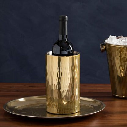Three brass ice buckets with bottles of wine and champagne on a wooden table against a dark background.