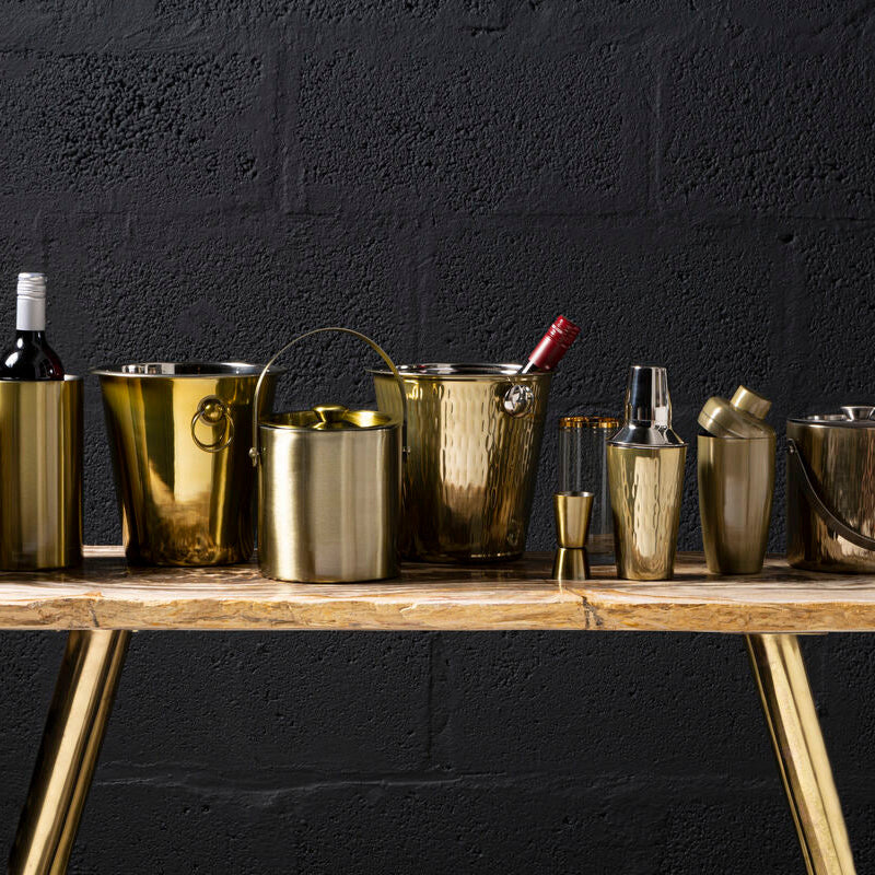 Set of gold ice buckets and bottles on a wooden table against a black background