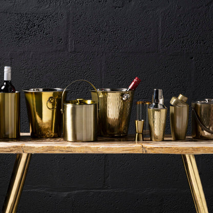Set of gold ice buckets and bottles on a wooden table against a black background