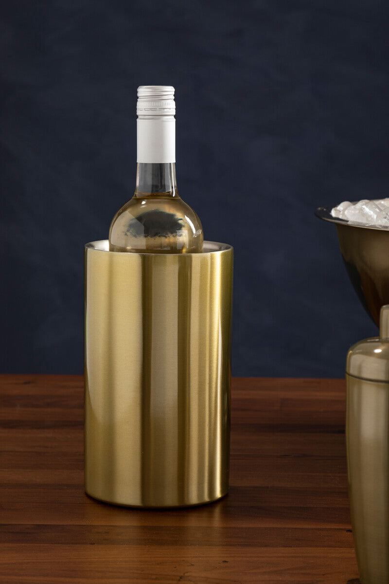 Gold wine cooler with a bottle of white wine on a wooden surface against a dark background
