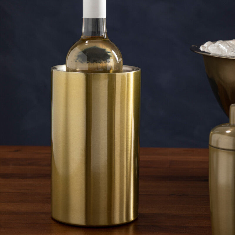 Gold wine cooler with a bottle of white wine on a wooden surface against a dark background