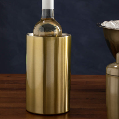 Gold wine cooler with a bottle of white wine on a wooden surface against a dark background