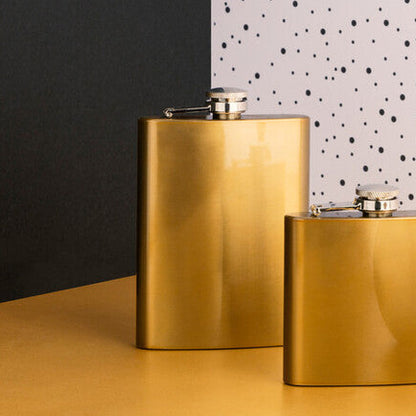 Three gold flasks on a table with a polka dot wall in the background