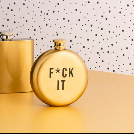 Three gold flasks on a table with a polka dot wall in the background