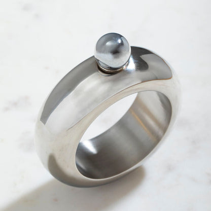 Silver ring with a central sphere on a marble surface