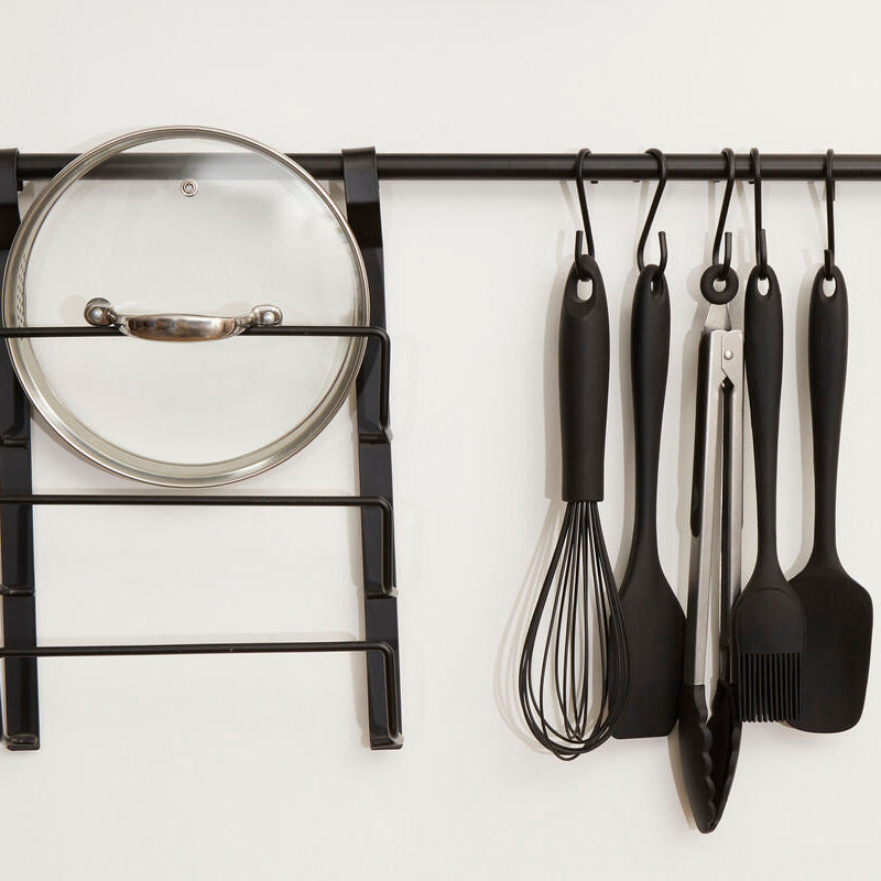 Wall-mounted kitchen utensil rack with various tools on a white background