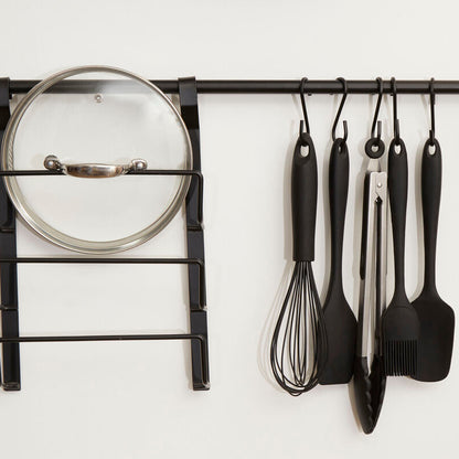Wall-mounted kitchen utensil rack with various tools on a white background
