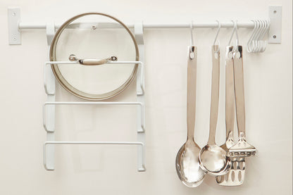 Kitchen utensils hanging on a white wall-mounted rack