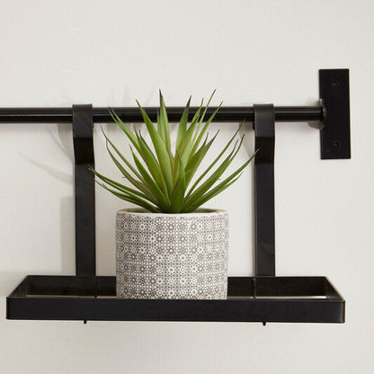 Black metal wall shelf with a potted plant on a white background