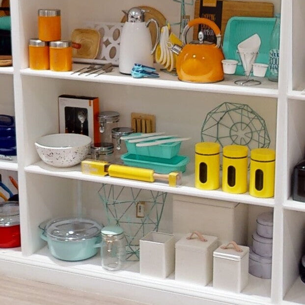 Shelving unit with kitchenware including jars, bowls, and a teapot.