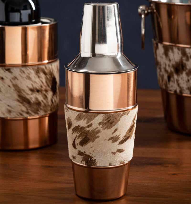 Copper and cowhide-patterned cocktail shaker on a wooden surface with dark background