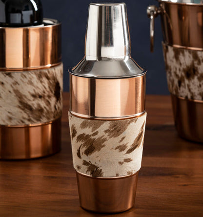 Copper and cowhide-patterned cocktail shaker on a wooden surface with dark background
