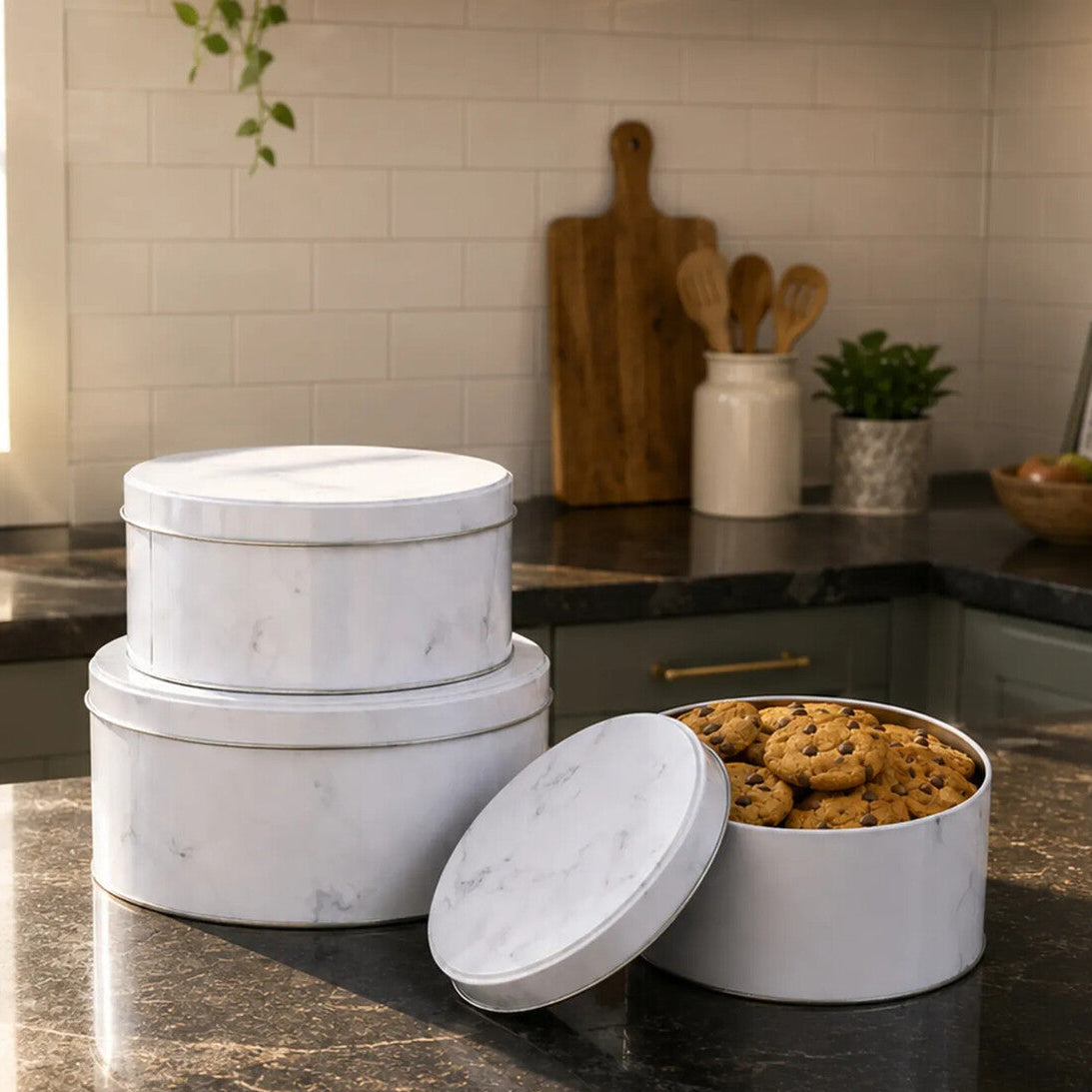 Set of three white marble-patterned storage containers on a kitchen counter with cookies inside.