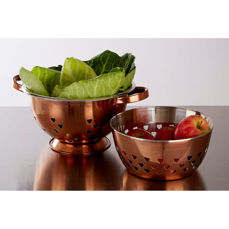 Copper colander and bowl with heart-shaped holes on a white background