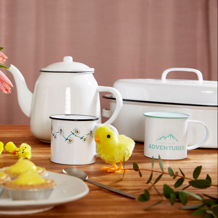 Tea set with teapots, cups, and pastries on a wooden table with a blurred background