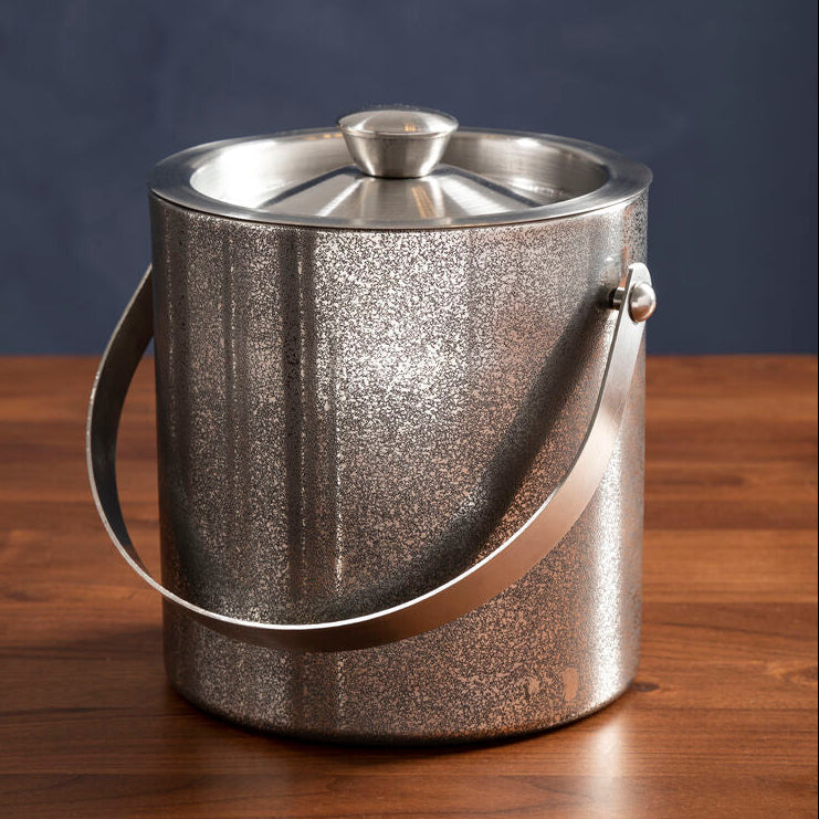 Silver ice bucket on a wooden surface with a dark blue background