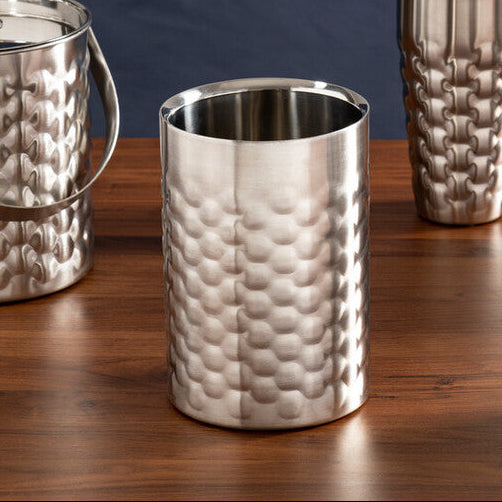 Set of silver cocktail shakers and ice buckets on a wooden surface with a dark blue background