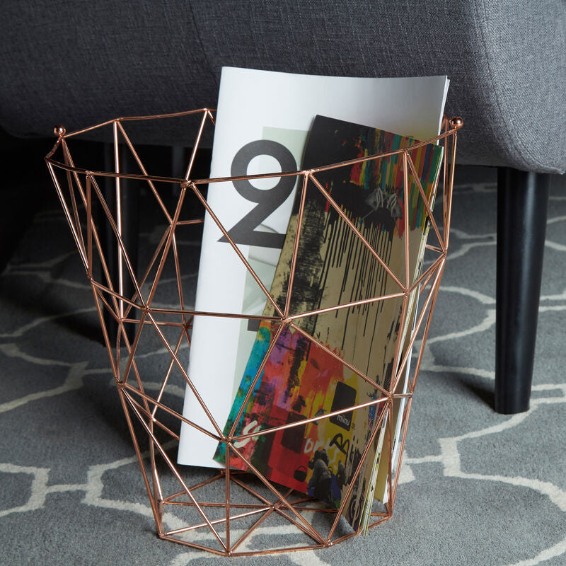 Geometric copper magazine holder with books on a patterned carpet