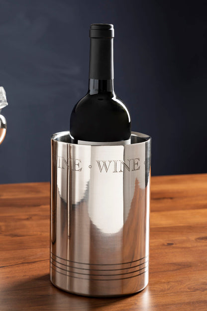 Silver wine cooler with a bottle of wine on a wooden surface against a dark background