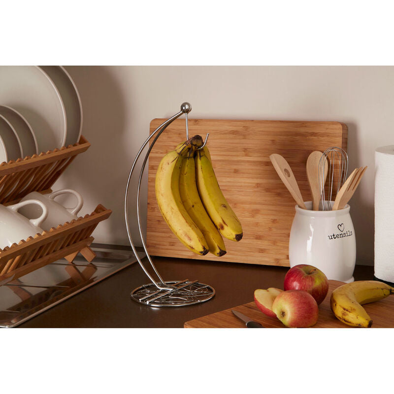 Banana holder with bananas on a kitchen counter with apples and utensils.