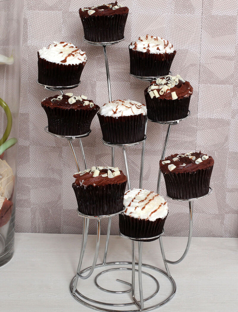 Chocolate cupcakes with white frosting on a metal stand against a patterned wall.