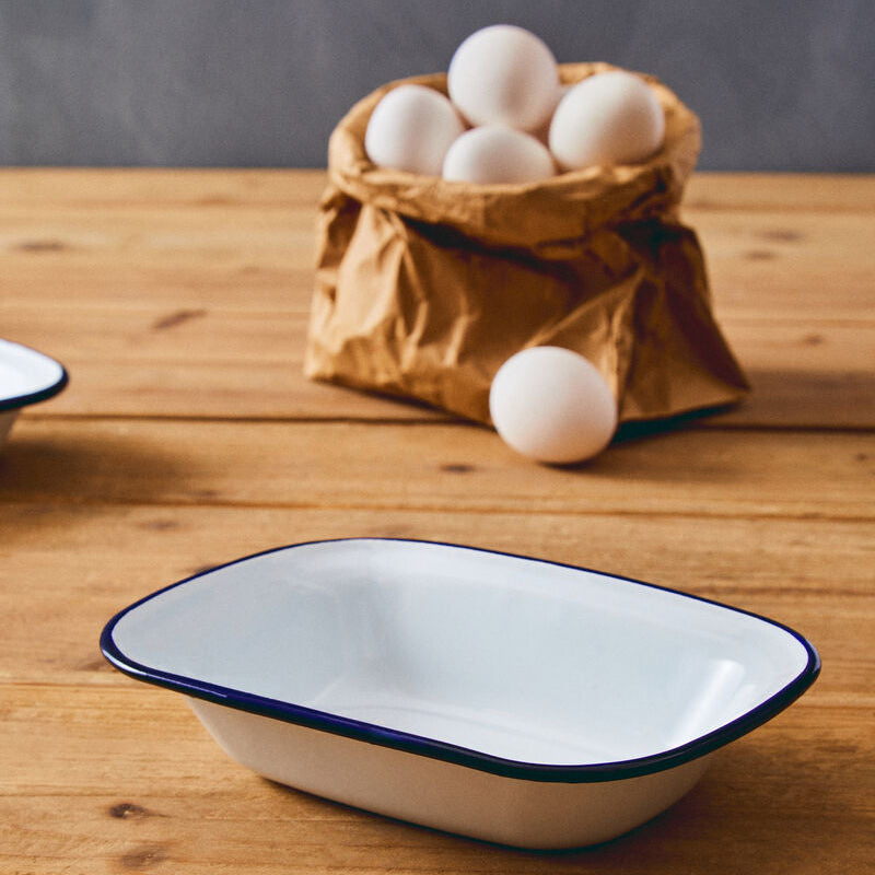 Enamelware dish on a wooden table with eggs in a paper bag in the background