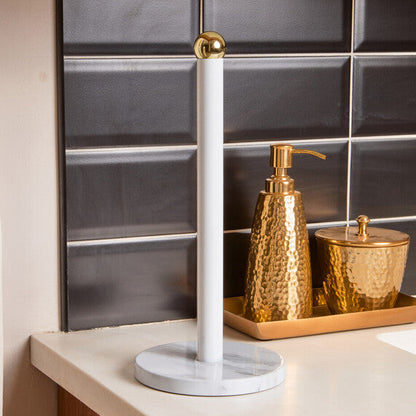 Decorative items including a white candle, gold soap dispenser, and canister on a countertop with a tiled wall background.
