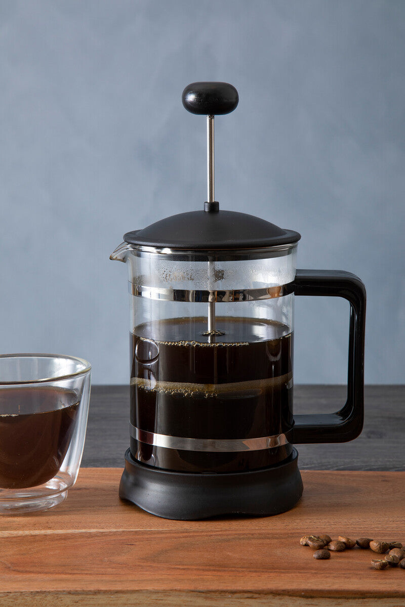 French press with coffee and a glass of coffee on a wooden surface