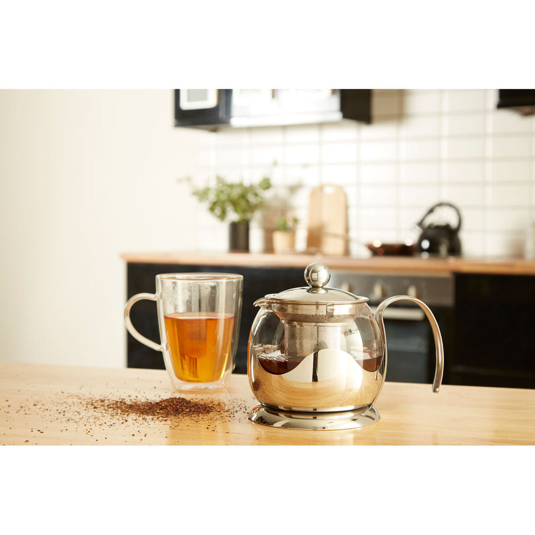 Tea pot and glass mug with tea on a kitchen counter