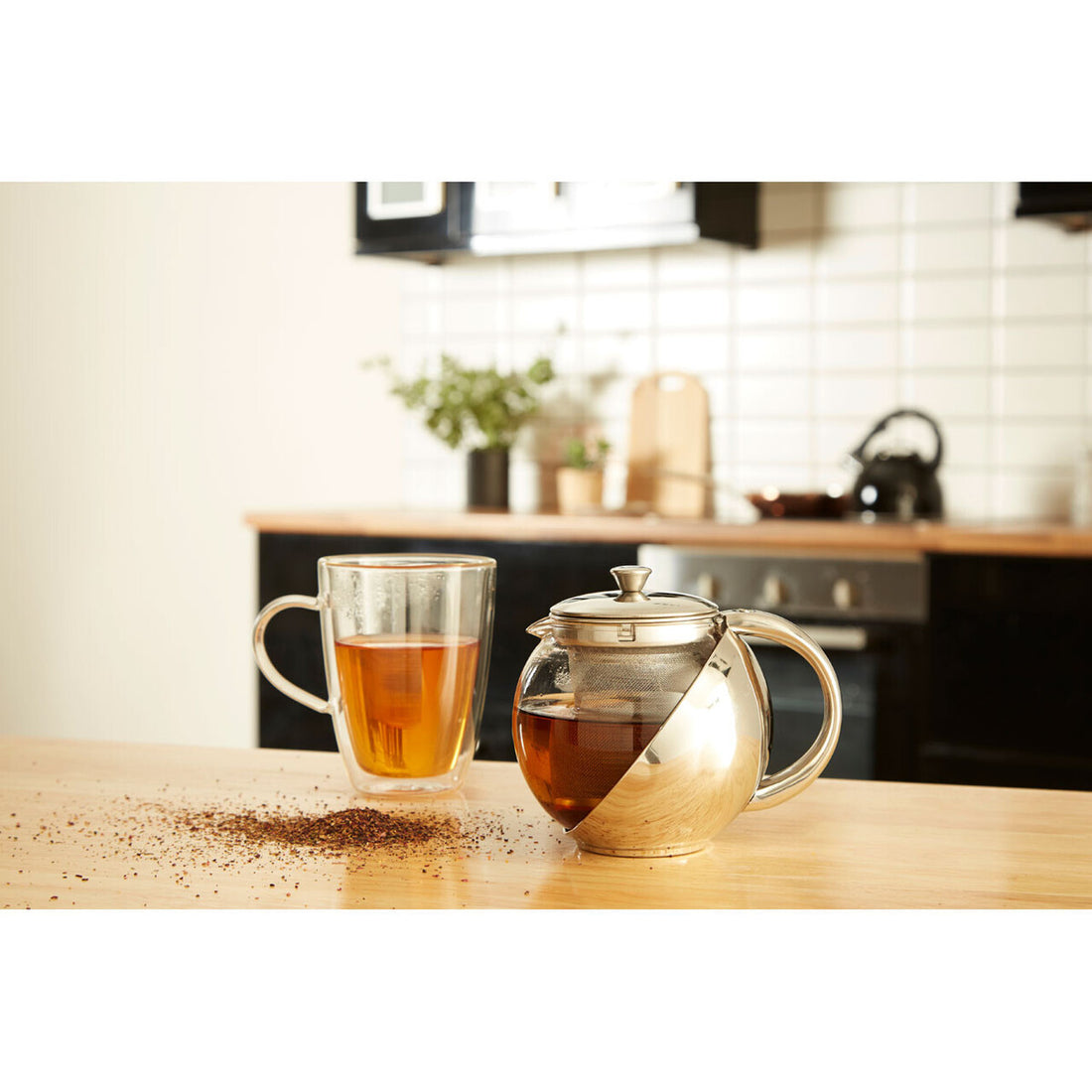 Tea pot and glass mug with tea on a kitchen counter
