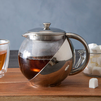 Tea pot with a glass of tea and sugar cubes on a wooden board against a gray background