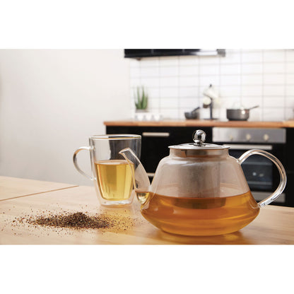 Tea-making setup with glass teapot and mug on a kitchen counter.