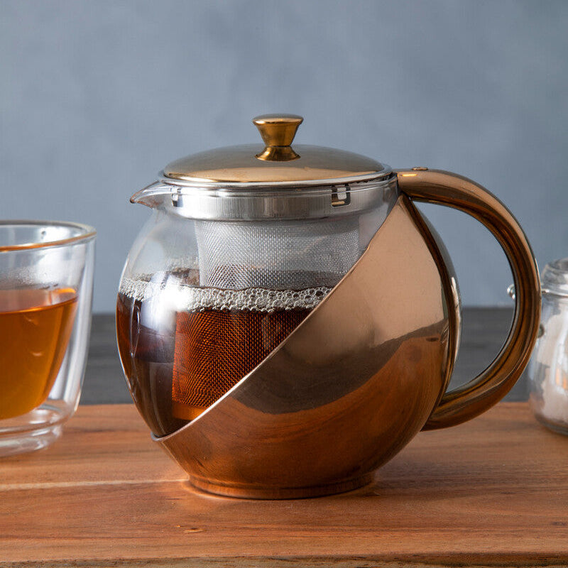 Tea pot with a glass of tea on a wooden surface