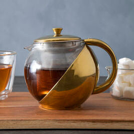 Tea pot with a glass lid on a wooden surface with a gray background