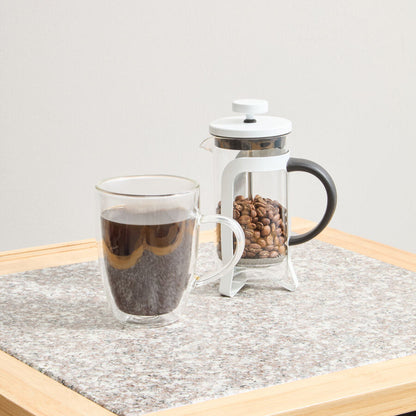 Clear glass mug with coffee and French press on a wooden surface