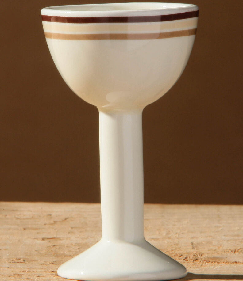 White ceramic goblet with brown stripes on a wooden surface and brown background