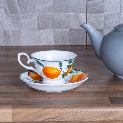 Teacup, saucer, and teapot on a wooden surface with a tiled wall background