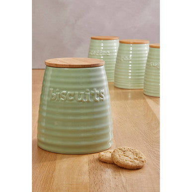 Green ceramic cookie jar with wooden lid on a wooden surface
