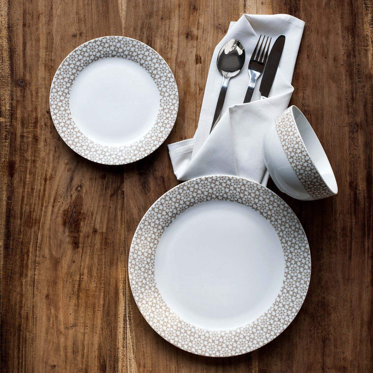 Dinnerware set with plates, cups, and cutlery on a wooden table