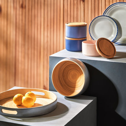 Set of ceramic bowls and plates on a modern surface with a wooden background