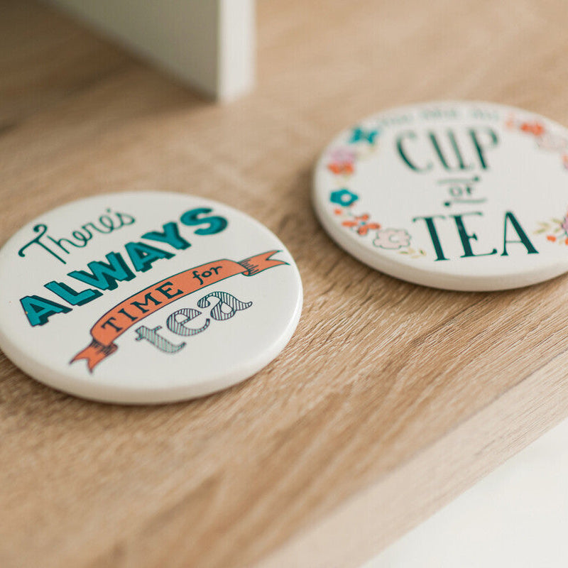Two ceramic coasters with tea-themed designs on a wooden surface.