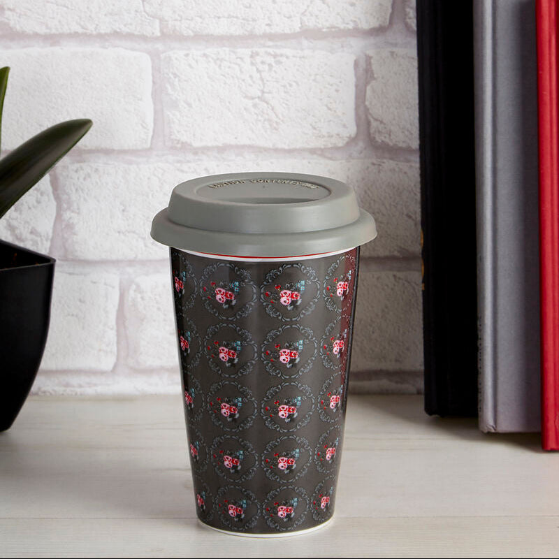 Reusable coffee cup with pink pattern on a white surface with books and flowers in the background