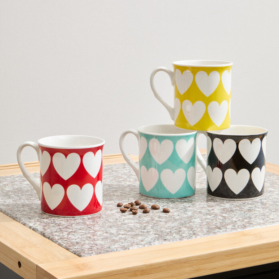 Four mugs with heart patterns on a wooden surface.
