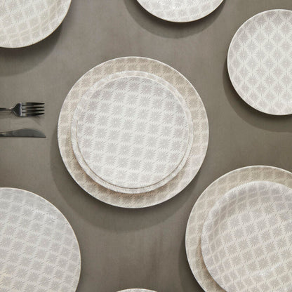 Set of white textured plates and silverware on a brown surface